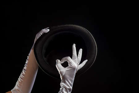 Hand gestures. Showman shows disappearing tricks in a hat, white gloves and black top hat,の写真素材