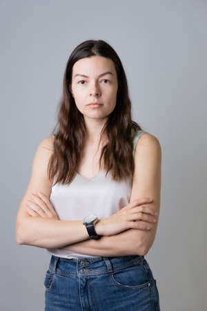 Portrait of a young woman of 30-40 years, calm and confident brunette in jeans and a light top,