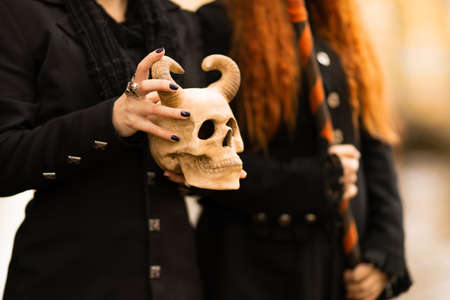 a witch holds in hands the skull of a demon. Halloween, a young woman at the carnival like a witch,の写真素材