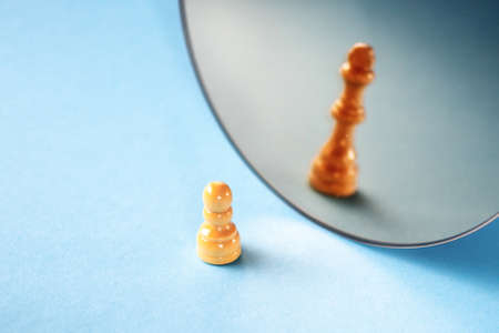 Career ambitions, concept. A chess piece on a blue background, a pawn sees itself as a queenの写真素材