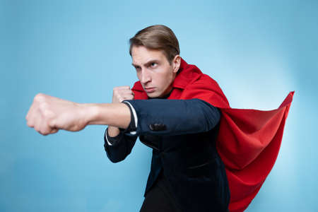 The superhero protects. A young man in a suit with a red cape, super man.の写真素材