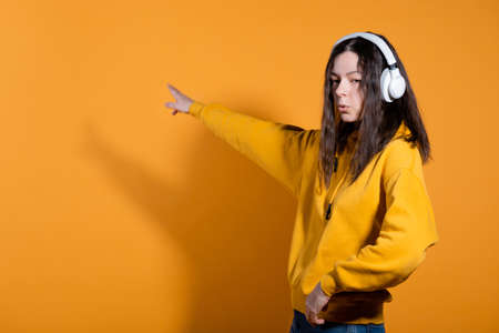 Music lovers enjoy music. A young woman in a yellow hoodie with white wireless headphones,の写真素材