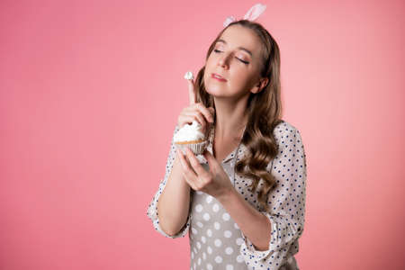 young charming female pastry chef tastes a muffin with cream. A cook in a polka-dot apron.の写真素材