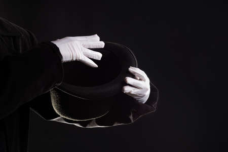 Hand gestures. Showman shows disappearing tricks in a hat, white gloves and black top hat,の写真素材