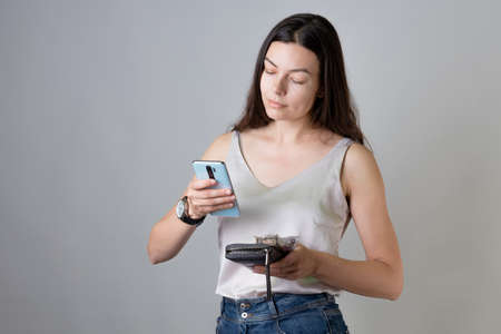Check your bank account in the app on your smartphone. A young woman with a wallet and phoneの写真素材