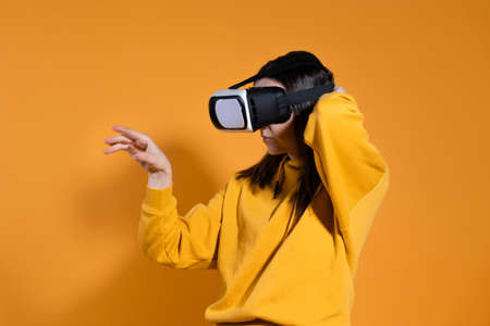 young woman with a virtual reality device on a yellow background.