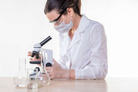 lab technician looks into the eyepiece of a microscope, a young female doctor