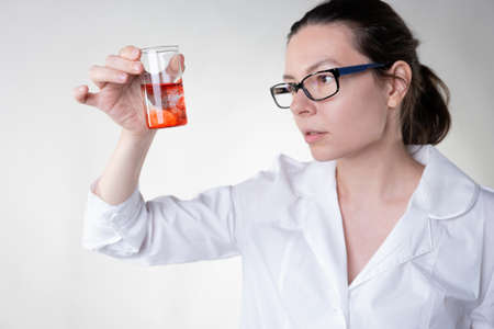 A doctor in a white coat uses a flask to study some red liquid,の写真素材