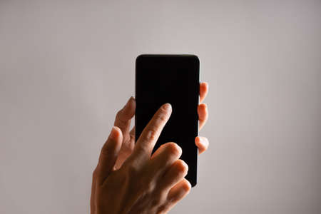 Use mobile apps, scroll. Smartphone, the female hand uses the touchpad.