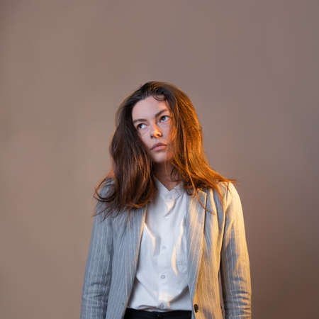 skeptical young business woman looks wearily away, a brunette in a gray suitの写真素材