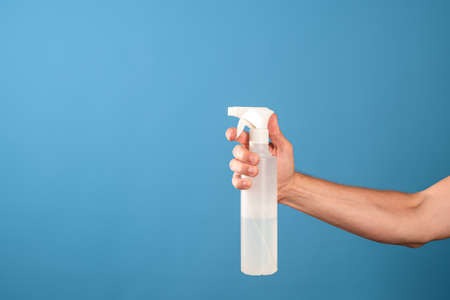 Do the cleaning of the house, a call for cleanliness and order, a mans hand holds a cleaning agent with a spray gun, blue backgroundの写真素材