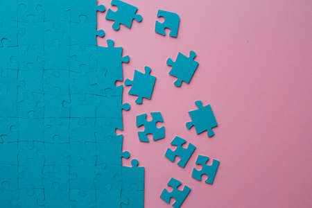 A set of puzzles, the process of collecting in a large pattern. Teamwork and problem solving, concept. Blue mosaic on pinkの写真素材