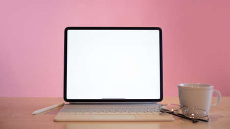 a minimalistic workplace for a designer or developer. A laptop and a cup of coffee are nearby. Bright pink backgroundの写真素材