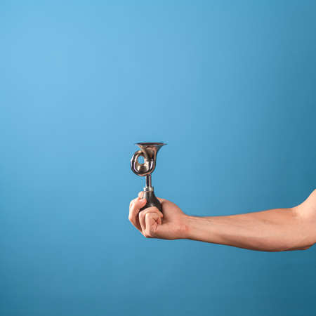 Attention, vintage bicycle horn, loud signal to attract attention. Horn in a mans hand, blue background.の写真素材