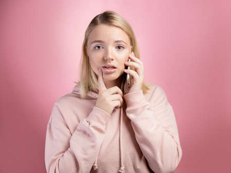 A surprised young woman with a phone. Shocking phone conversation, emotionsの写真素材