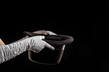 Hand gestures. illusionist holds a hat in his hands and shows magic and tricks. Black backgroundの写真素材