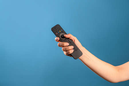 Watch new TV series and movies at home on streaming services, the TV remote control is in a female...