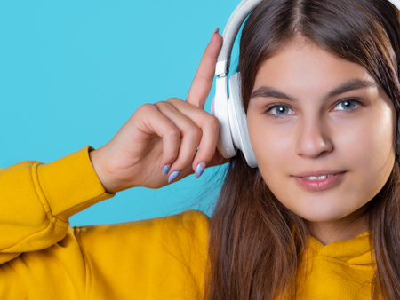 Music lover, a young woman with headphones, listening to music. A young brunette in a bright yellow...