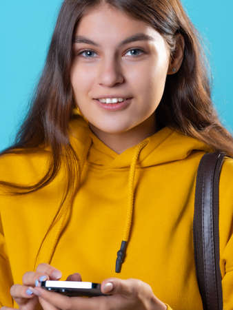 Mobile communication, use social network applications and instant messengers for correspondence. young brunette in yellow uses smartphone to communicate and search information on Internet, close-upの写真素材