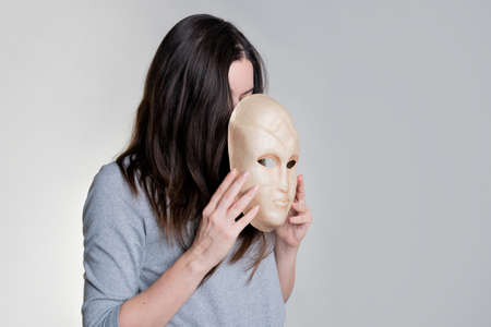 Complexes because of appearance. A young woman hides her face behind a mask, skin problems, the concept of cosmetology and beauty industry.の写真素材