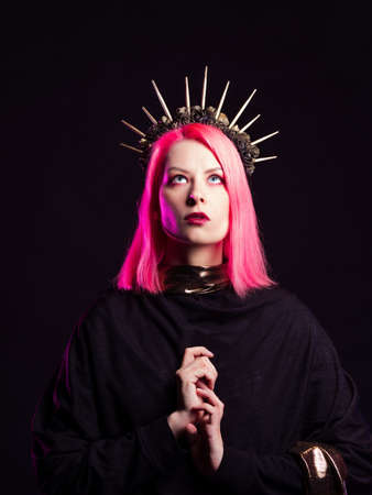A gothic diva with pink hair in a royal image, a crown with roses and rays on her head, hands folded in a prayer gesture.の写真素材