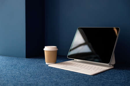 Thin mobile laptop coffee to take away, a freelancers workplace. Blue background, white laptop, mobile computer.の写真素材
