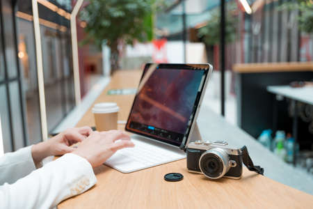 A freelance photographer works remotely, a thin mobile computer with a photo on the screen and a camera in the foreground. Creative work, retouching or creating designs.の写真素材