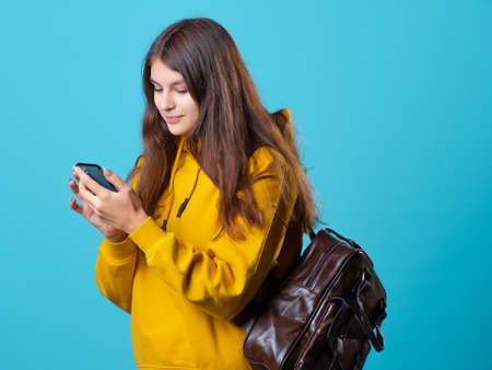 Mobile communication, use social network applications and instant messengers for correspondence. A young brunette in yellow uses a smartphone to communicate and search for information on the Internet.の写真素材