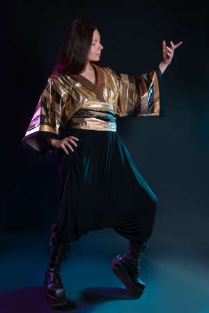 Stylish and daring image, futuristic fashion. A young woman in a multicultural outfit mixing Asian and European style. Stylish brunette posing pathetically, photo in the studio on blackの写真素材