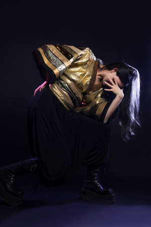 Stylish and daring image, futuristic fashion. A young woman in a multicultural outfit mixing Asian and European style. Stylish brunette posing pathetically, photo in the studio on blackの写真素材