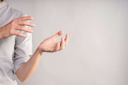 Two womens hands are holding something in their palms, businesswoman in a casual gray shirt makes a hand gestureの写真素材