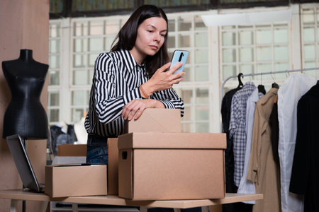 Small business, tailor shop, costume designers workshop. A young female entrepreneur in the workplace, packing parcels and running an online store. Portrait in the interiorの写真素材