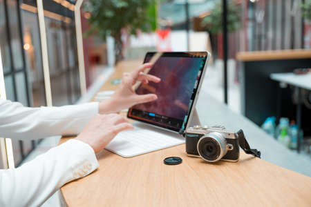 A freelance photographer works remotely, a thin mobile computer with a photo on the screen and a camera in the foreground. Creative work, retouching or creating designs.の写真素材