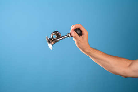 Attention, vintage bicycle horn, loud signal to attract attention. Horn in a mans hand, blue...