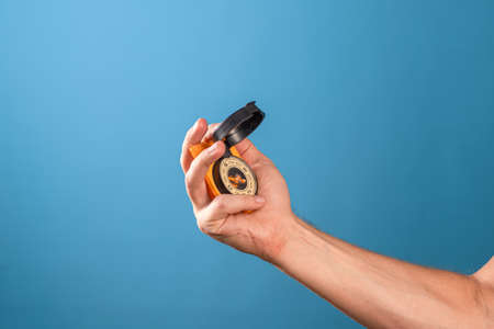 Help in navigating the terrain, find your location, concept. Magnetic compass in a mans hand, photo...