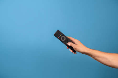 Manage home appliances, elements of a smart home with remote control, comfort for life. The control panel is in a mans hand. Photo on a blue backgroundの写真素材