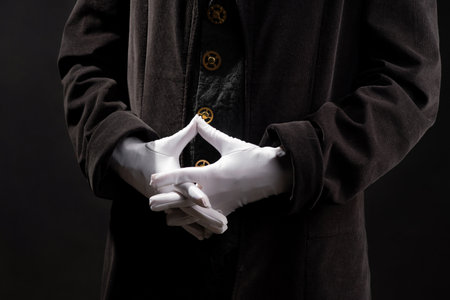 Hand gestures. magician clasped his hands together. Showman or magician illusionist in white gloves on a black background.の写真素材