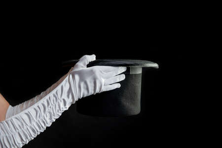 Hand gestures. illusionist holds a hat in his hands and shows magic and tricks. Black backgroundの写真素材