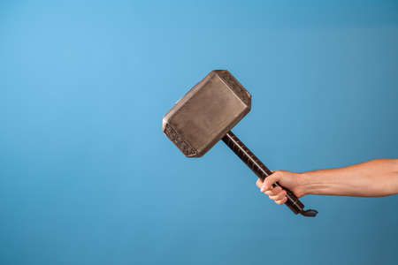 Be a hero, perform a feat. The Scandinavian hammer of Thor, Mjolnir in a mans hand. Photo on a blue backgroundの写真素材