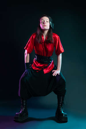 Stylish and daring image, futuristic fashion. A young woman in a multicultural outfit mixing Asian and European style. A red kimono shirt and trousers, a black mask on his head, no name bullyの写真素材