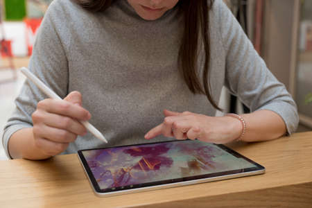 A digital artist draws on a graphic screen tablet, modern technologies for creativity. A young woman artist or designer uses a tablet to drawの写真素材