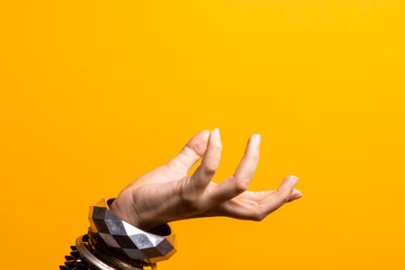 Hand gestures. Womens hand with lots of bracelets, youth fun style. bright yellow backgroundの写真素材