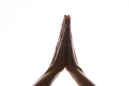 Praying hands on a white background. Light from above. Hands folded in prayer. Hand gestures, isolated on white, contour lighting, contrast.の写真素材