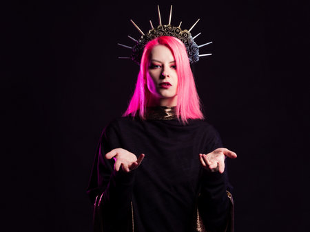 A gothic diva with pink hair in a royal image, a crown with roses and rays on her head, open arms stretched out to youの写真素材