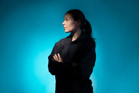 Think, there is an idea. Young woman portrait side view, face partially illuminated, thoughtful look up, dark blue backgroundの写真素材