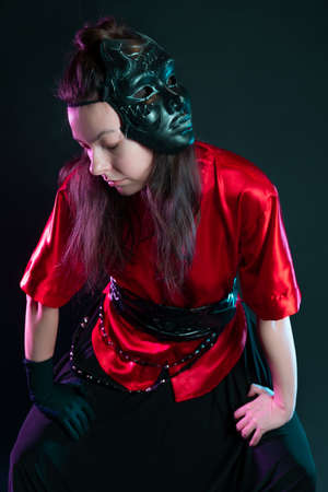 Stylish and daring image, futuristic fashion. A young woman in a multicultural outfit mixing Asian and European style. A red kimono shirt and trousers, a black mask on his head, no name bullyの写真素材