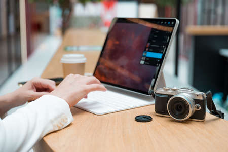 A freelance photographer works remotely, a thin mobile computer with a photo on the screen and a camera in the foreground. Creative work, retouching or creating designs.の写真素材