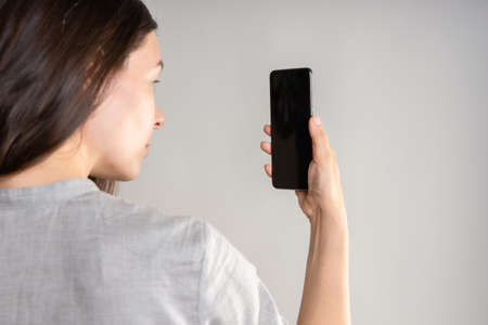 woman holds the smartphone in front of her eyes and unlocks the phone via face id. Face recognition...