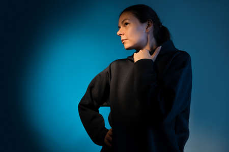 Think, there is an idea. Young woman portrait side view, face partially illuminated, thoughtful look up, dark blue backgroundの写真素材