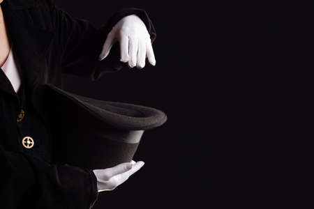 Hand gestures. illusionist holds a hat in his hands and shows magic and tricks. Black backgroundの写真素材